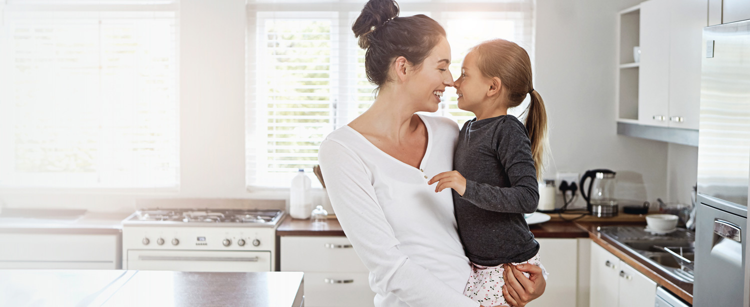 Mutter mit Tochter auf dem Arm, entspannt in der Küche